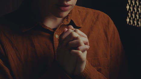close-up of female penitent praying with hands clasped in confession
