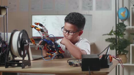 asian cute boy thinking while working about a cyborg hand at home