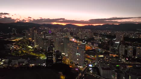 Aerial-view-around-the-illuminated-cityscape-of-Santa-Fe,-evening-in-Mexico-city