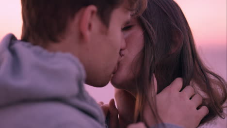 Unhappy-couple-making-up-and-kissing-on-beach-at-sunset-sad-woman-being-comforted-by-strong-handsome-man