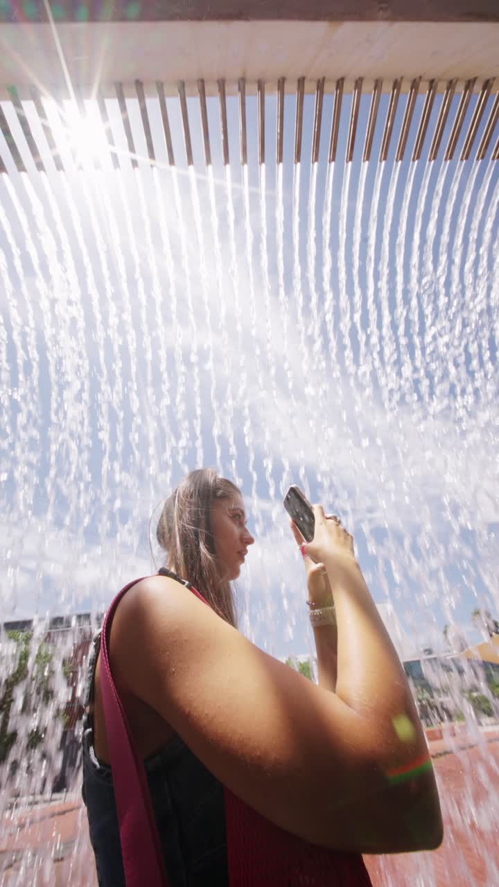 Young Woman Photographing a Modern Water Fountain