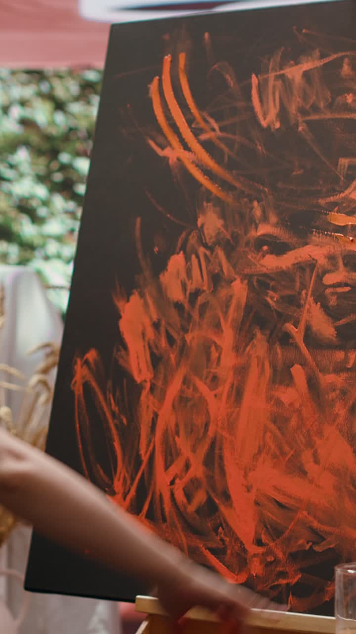 Artista che dipinge arte astratta con le dita su tela nera all'aperto.