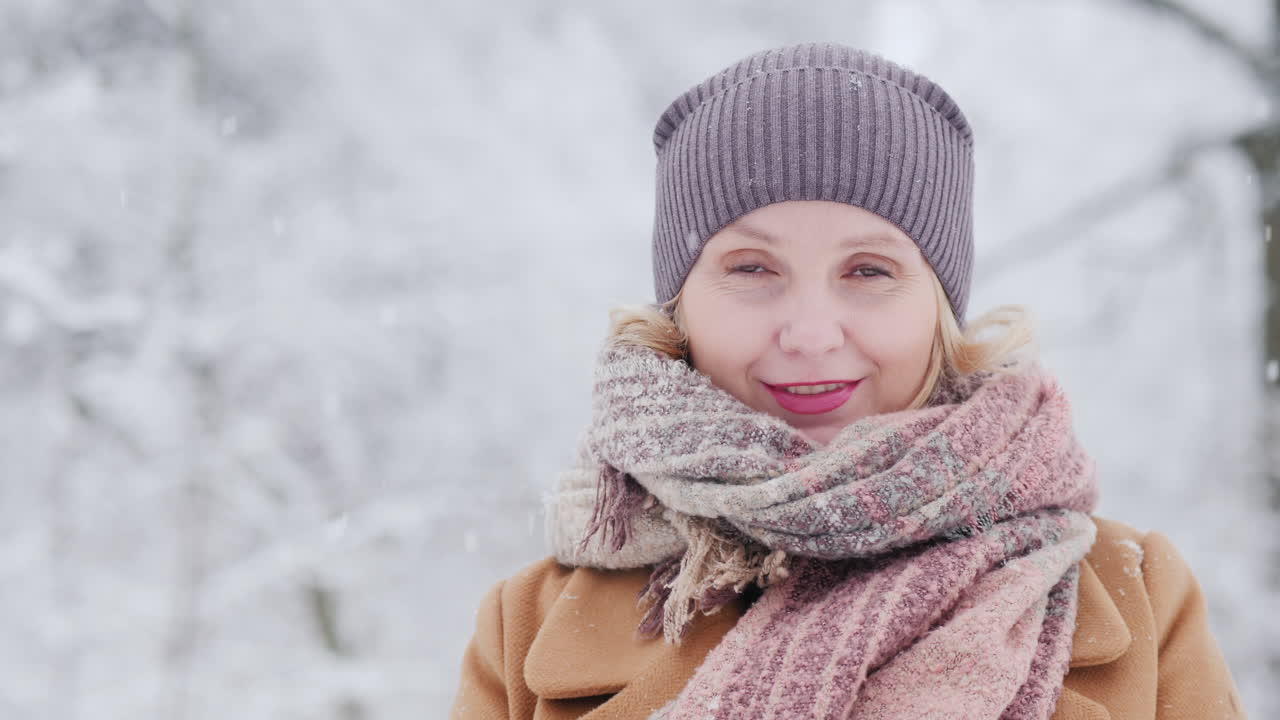 retrato de una mujer de mediana edad en un parque de invierno mira hacia el video de la cámara 4k
