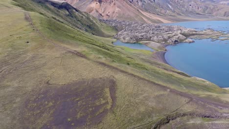 aerial fixed drone view from bottom to top of lava flow falling into frostastaðavatn lake in the landmannalaugar region