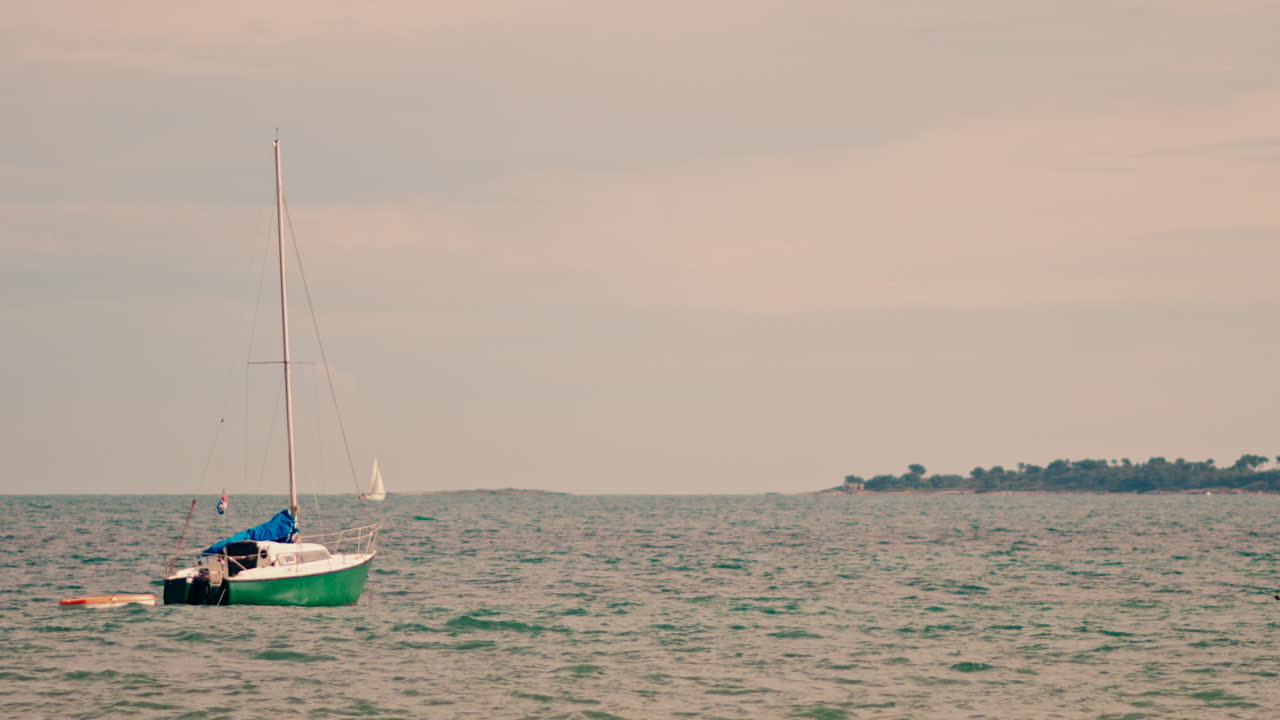 Small white and green boat floating on the Mediterranean Sea on a cloudy day