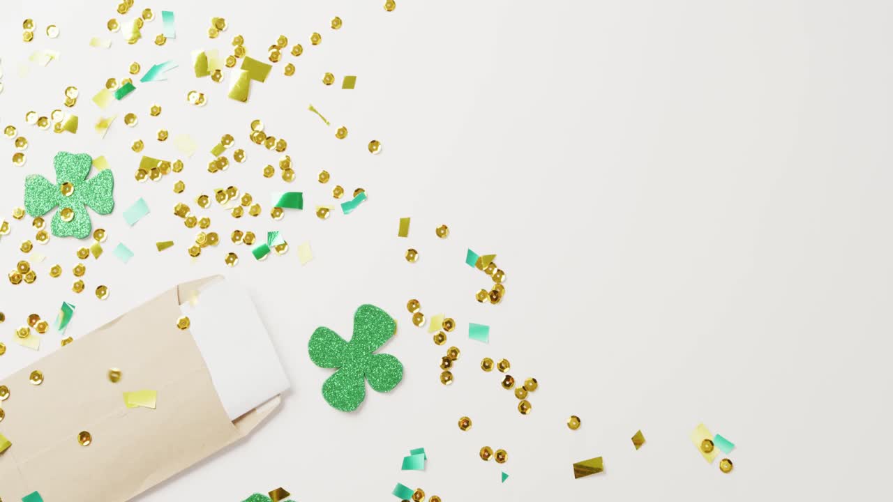 Video of st patrick's green shamrock leaves and sequins with copy space on white background
