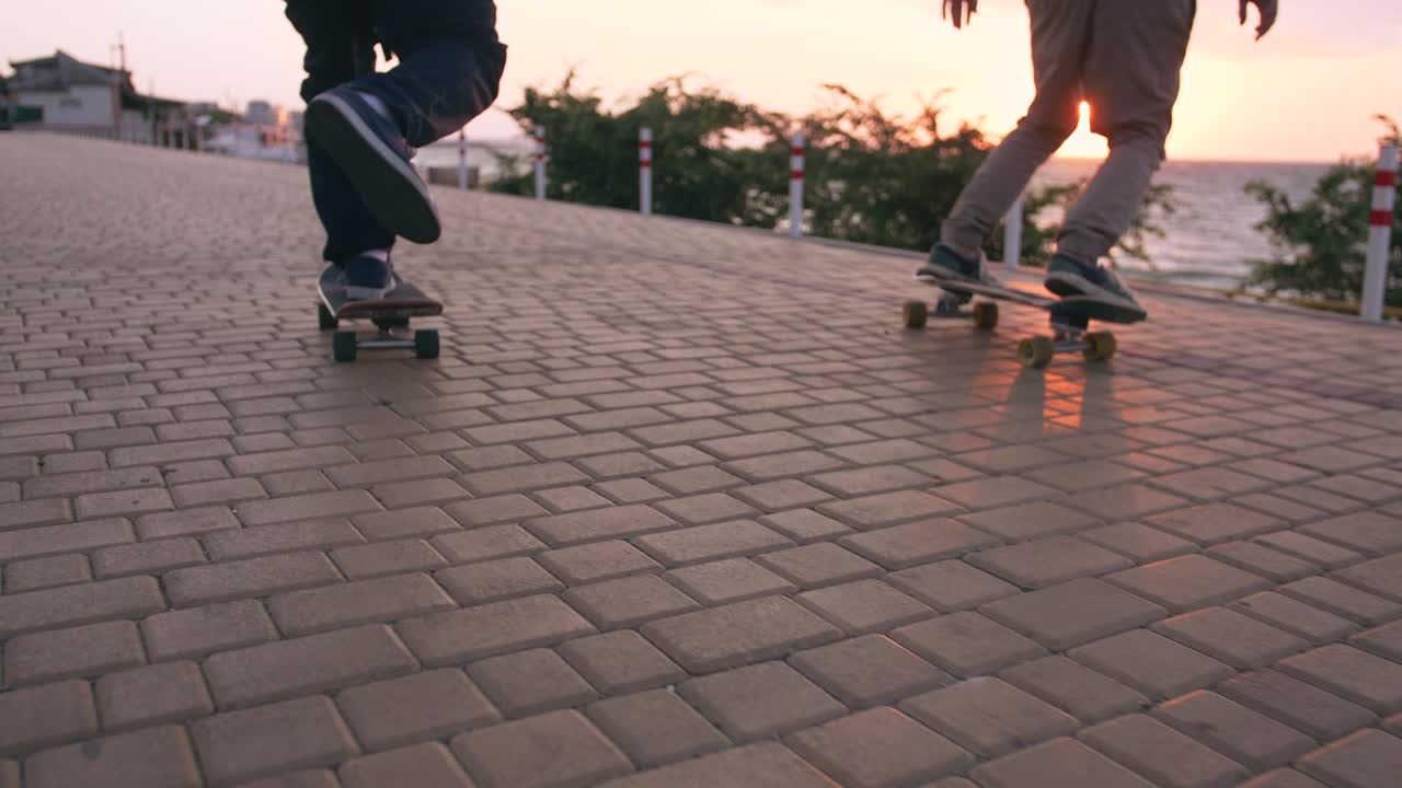 Group of young people skateboarding on the road in the early morning near the sea, close up shot