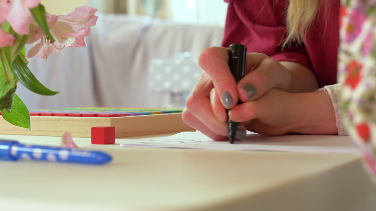 A mother helps her child learn how to draw by guiding their hand