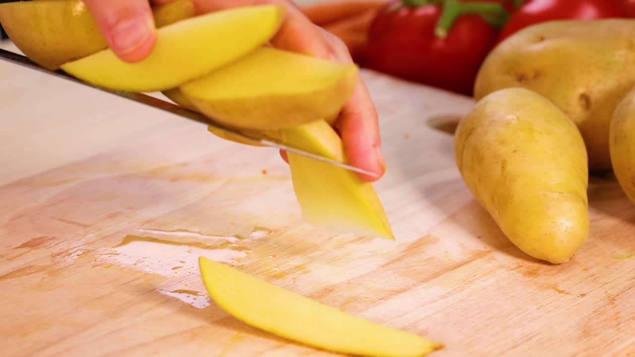 manos cortando patatas con verduras en el fondo