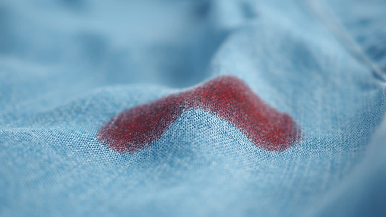 Close-Up of Red Liquid Stains Soaking into Blue Fabric