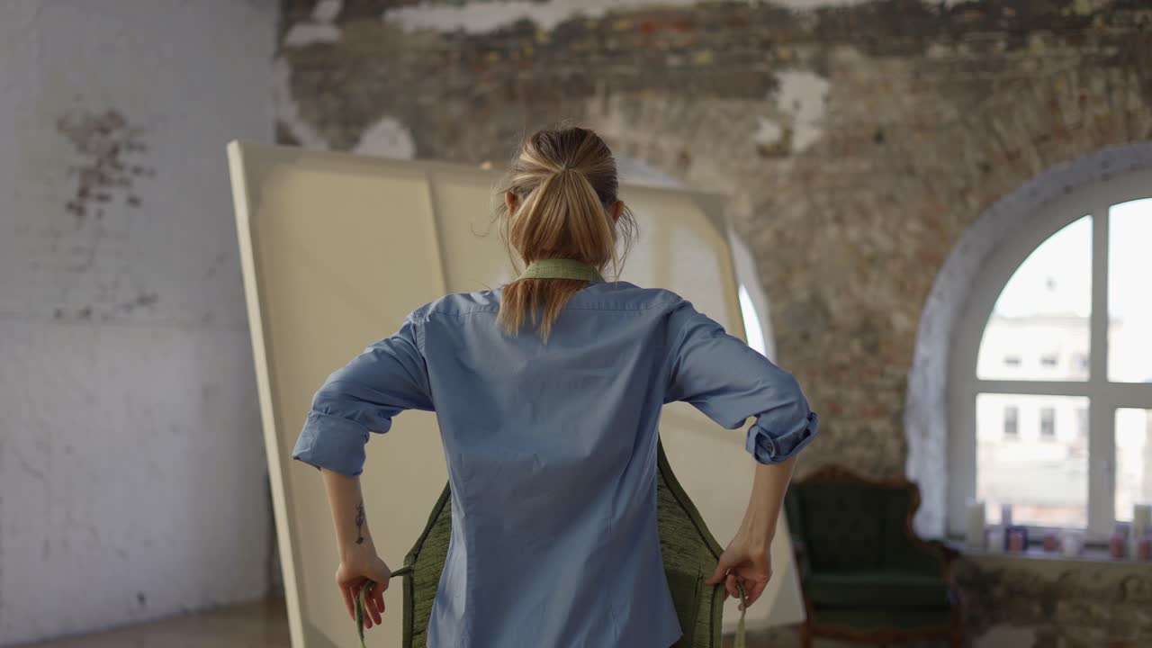 Unrecognizable woman put on apron to start painting in workshop