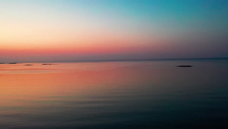 Drone-Lowering-over-Calm-Beautiful-Ocean-Sunrise-with-Small-Islands-on-the-Horizon