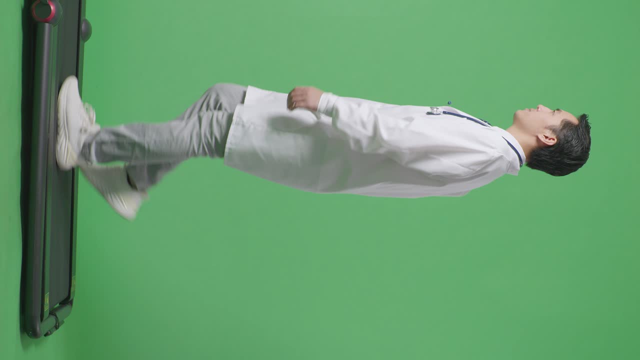 으로 볼 수 있는 전체 몸의 아시아 남성 의사는 스테토스코프를 가지고 병원에서 녹색 화면 배경에서 고 있습니다.