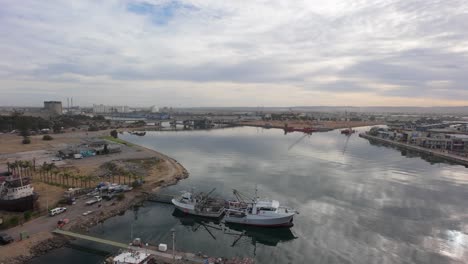 drone flight showing port adelaide river with boats with a boat yard behind them