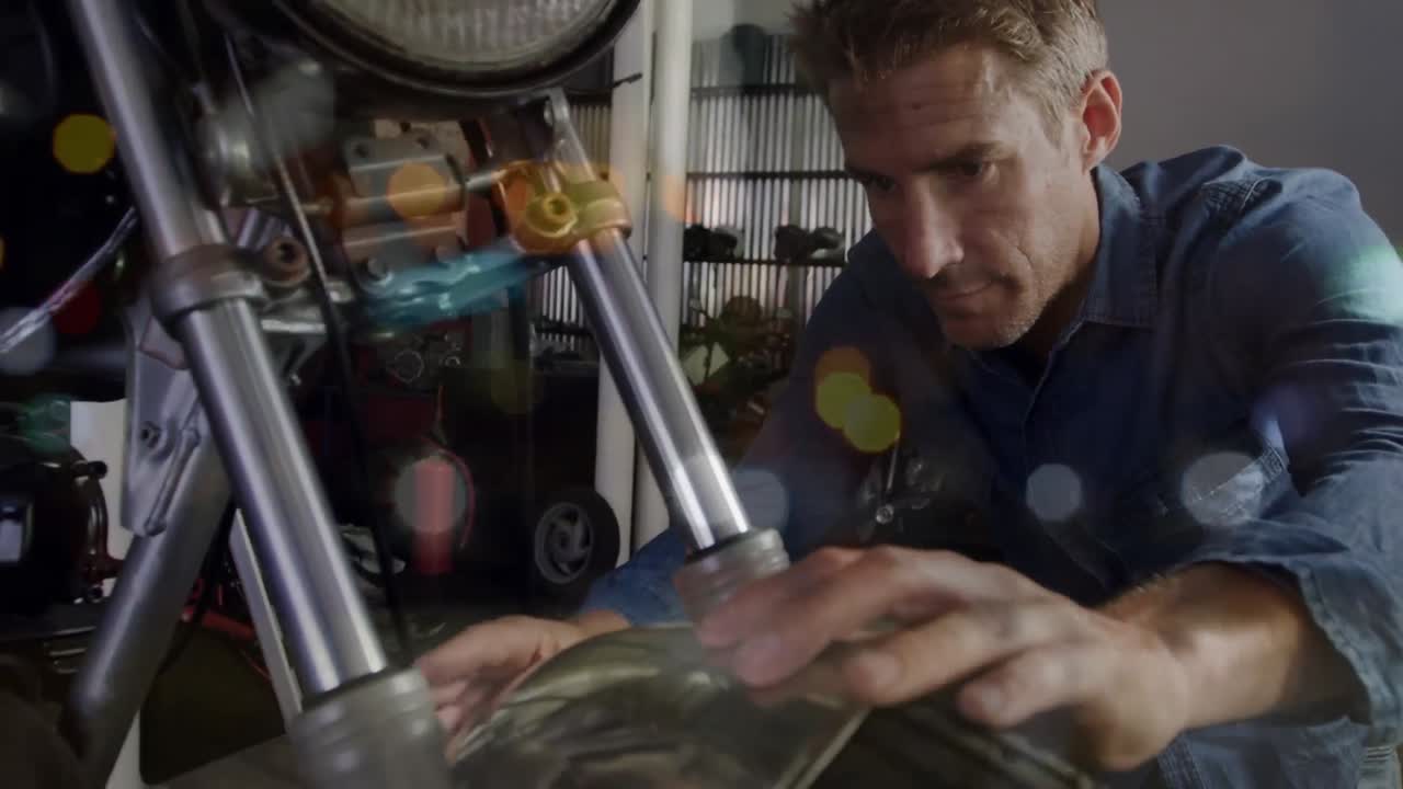 Animation of flickering lights over caucasian male mechanic fixing motorcycle
