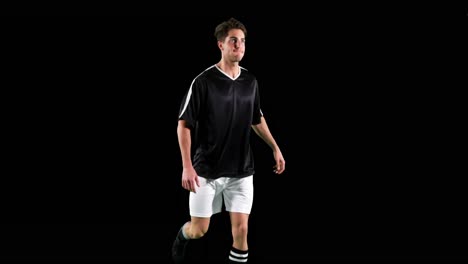 Athlete-practicing-soccer-against-black-background