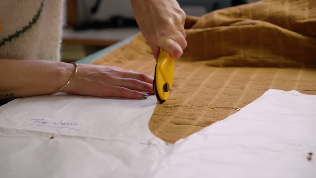 Seamstress using rotary cutter to cut cloth with sewing patterns
