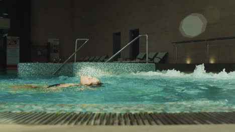 mujer hermosa nadando en la espalda en la piscina de spa. chica bonita relajándose en el jacuzzi