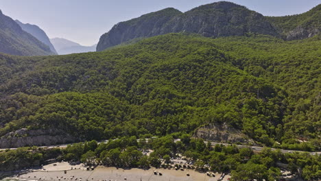 Antalya-Turquía-Antena-V50-Flyover-Topman-Beach-Con-Gente-Nadando-En-El-Mar,-Inclinar-Hacia-Arriba-Revela-Las-Cadenas-Montañosas-De-Tünek-Tepe,-Bosques-Costeros-Con-Densas-Vegetaciones---Filmado-Con-Cine-Mavic-3---Julio-De-2022