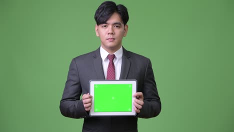 디지털 태블릿을 사용하는 젊은 잘생긴 아시아 사업가