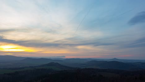 The-beautiful-indigo-sky-with-the-bright-orange-sunset-over-the-mountains-of-Ostrzyca-Proboszczowicka,-Poland---time-lapse