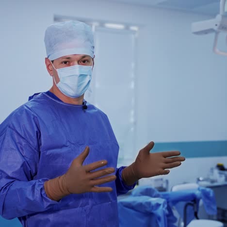 doctor talks on camera in the operating room. professional surgeon in blue medical uniform and mask explains important facts in surgery.