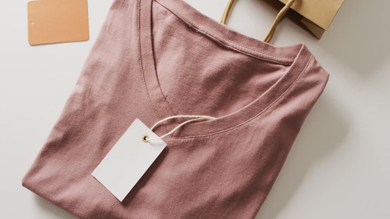 video di un close-up di una maglietta piegata marrone con tag su sfondo bianco