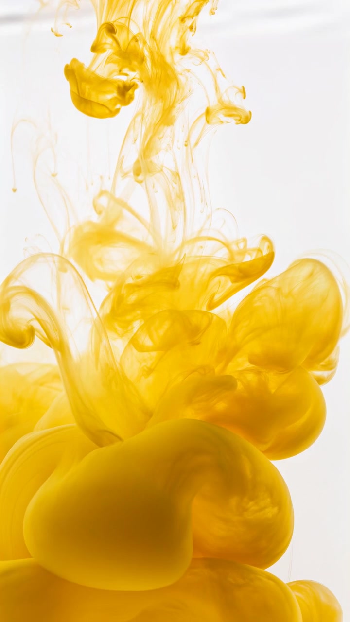 Primer plano de pigmento amarillo saturado dispersándose en líquido transparente, formando nubes densas y cremosas, filamentos translúcidos, velos suaves y texturas orgánicas en capas con luz de estudio limpia, con tinta, amarillo.