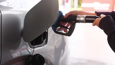 person refueling car at gas station