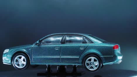 a tiny model metal sample car on a rotating stand with studio lights, close up shot, 4k video, silver wheels, black tires, doors and windows