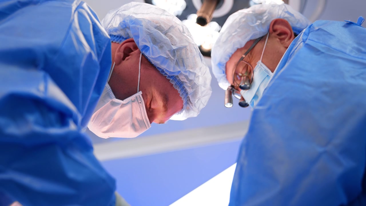 Volti concentrati di due medici che lavorano durante un'operazione. Vista dal basso. Neurochirurghi collaborano in sala operatoria