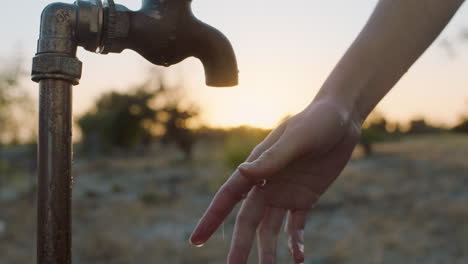 frau wäscht die hand unter dem wasserhahn auf einem ländlichen bauernhof bei sonnenuntergang süßwasser fließt aus dem wasserhahn