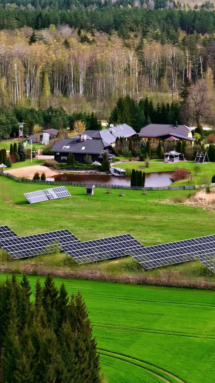 Solar panels in a lush green landscape, near a house by a pond, aerial view