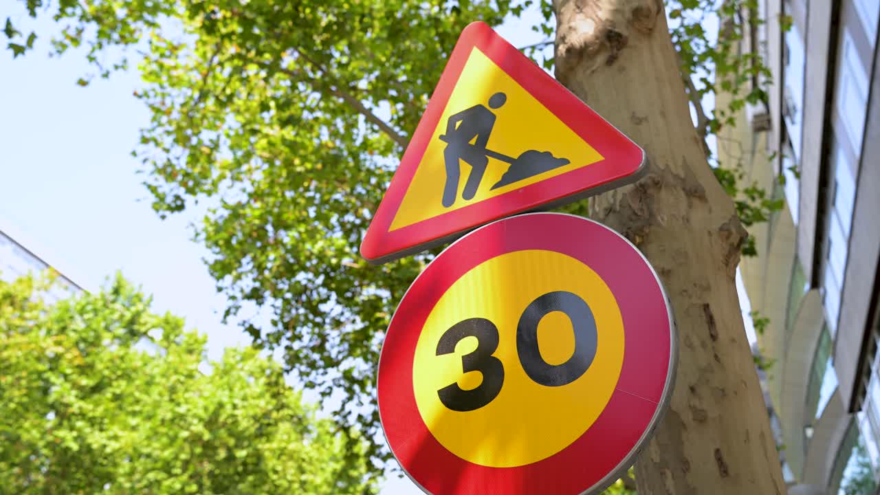 A "Road Work Ahead" warning sign and a 30 km per hour speed limit sign. A clear visual of traffic control and road safety measures for a construction zone