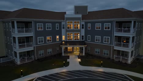 slow aerial pull back reveal of new retirement home building during blue hour