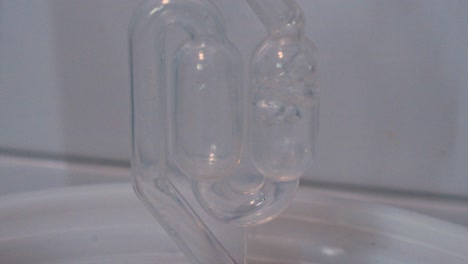 Detail-view-of-two-balls-of-a-laboratory-safety-tube-with-liquid-passing-through-generating-bubbles