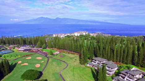 aerial view of luxury resort with golf court and sea in background during sunny day - beautiful mountain silhouette in backdrop - hawaii pacific ocean