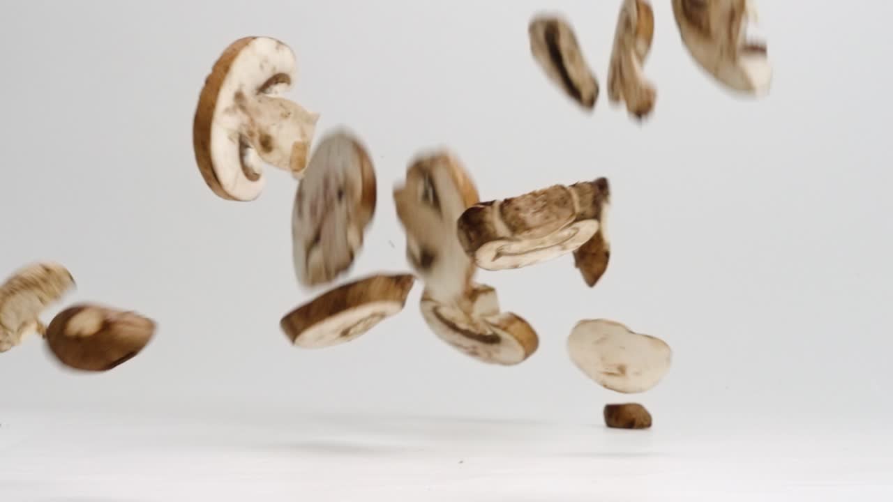 champiñones rebanados que caen sobre el fondo blanco del estudio y rebotan a cámara lenta en 4k