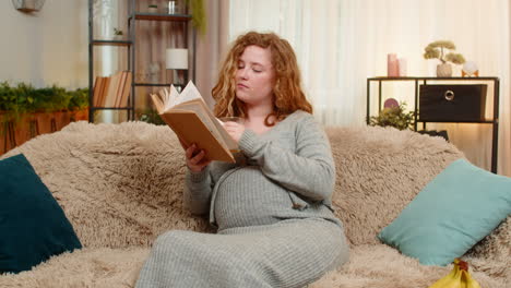 pregnant young woman drinking orange juice while reading pregnancy book at home calm relaxed mood