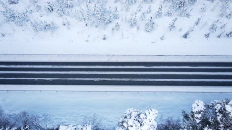 winter road with a red car driving horizontal