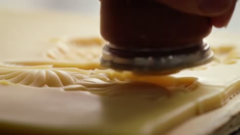 crafting intricate patterns: close-up of a skilled artisan stamping decorative designs into soft material using a precision tool