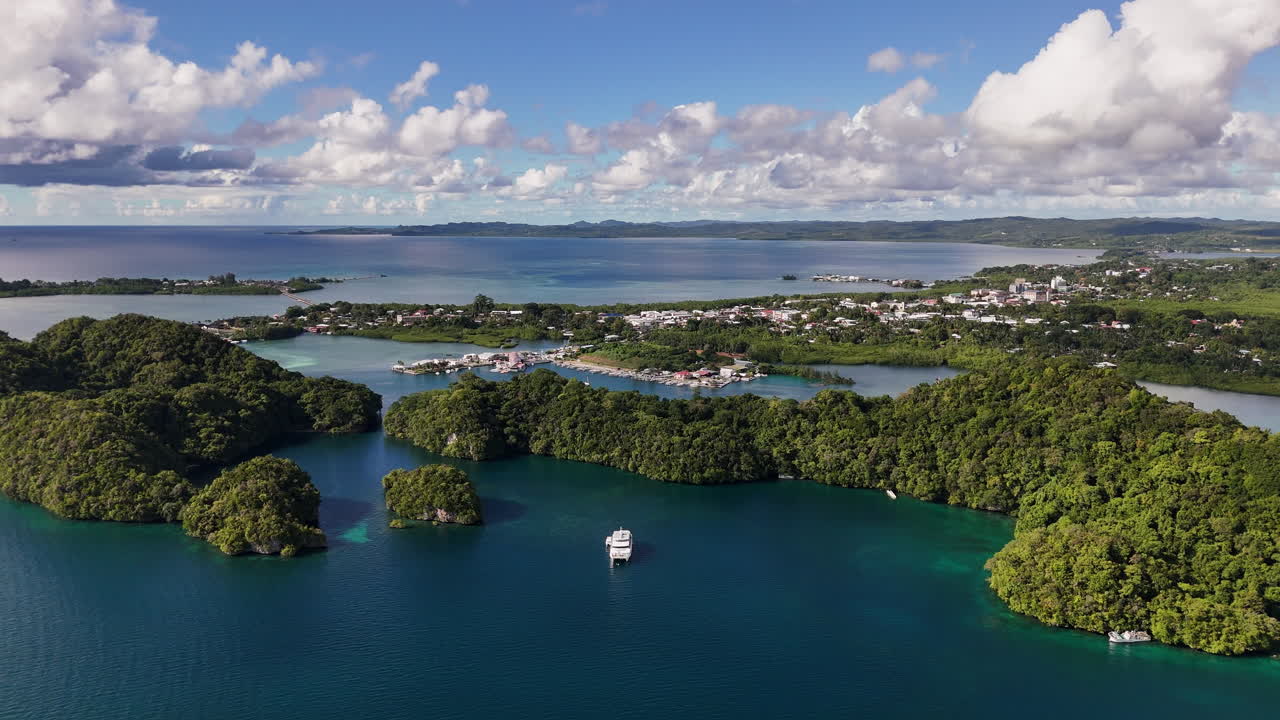 Aerial cinematic sequence circling and revealing the clear tropical waters and exotic landforms of Palau. Wide shot of resort and yacht