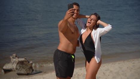 una pareja multiétnica se toma una selfie en la orilla del mar. una joven mujer feliz y un hombre en la playa.