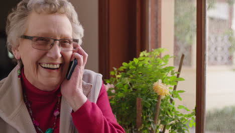 portrait of elegant elderly caucasian woman chatting on phone enjoying conversation wearing pink jersey retirement home