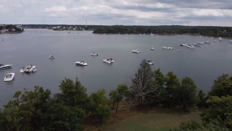 Gliding-over-trees-to-reveal-boats-in-a-inlet-near-World's-End-in-Hingham,-Massachusetts