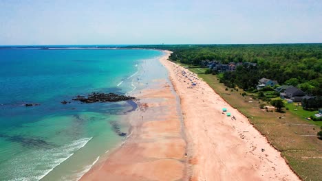 flying drone captures crowds at saco, maine beaches. tourists relax by the atlantic ocean, vacation houses overlook sand. summer waves, sun, and east coast scenery create a dreamy seashore escape.