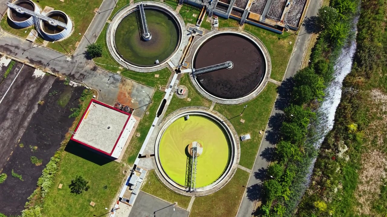 Wastewater treatment facility operates in daylight to process water and maintain environmental standards near urban area