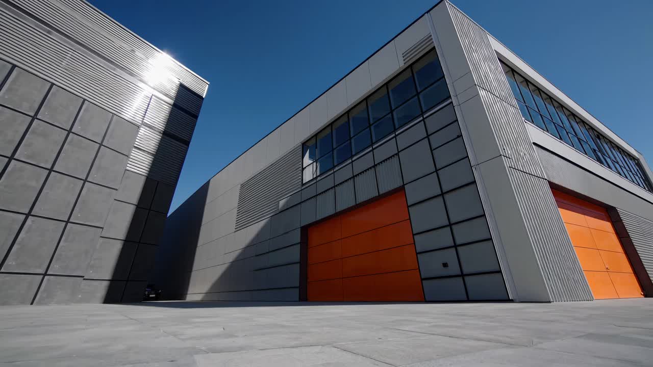 Low-angle video shot of modern industrial buildings with orange doors and sleek lines