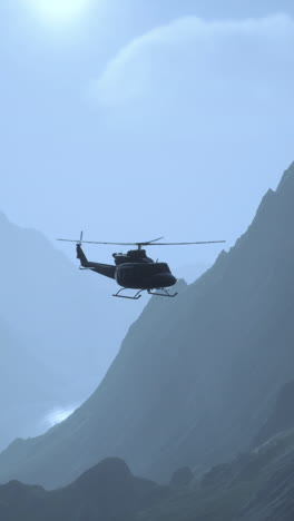 a military helicopter flies over a mountain range