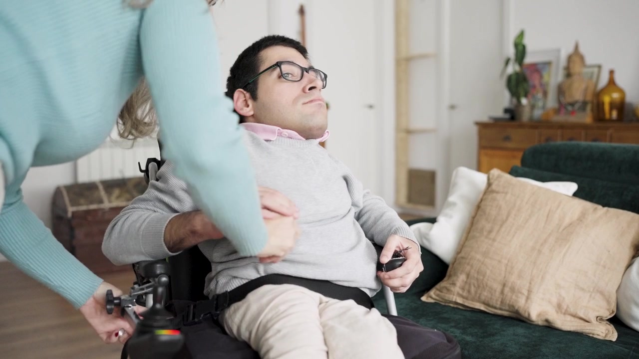 Caregiver Assisting Man in Electric Wheelchair at Home